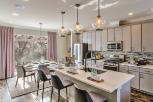 Modern kitchen with white cabinetry, pendant lighting, quartz countertops, and a breakfast bar with seating.