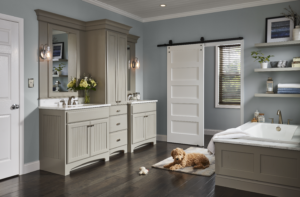 Transitional bathroom with double vanity, gray cabinetry, freestanding bathtub, barn door, and a dog resting on the floor.