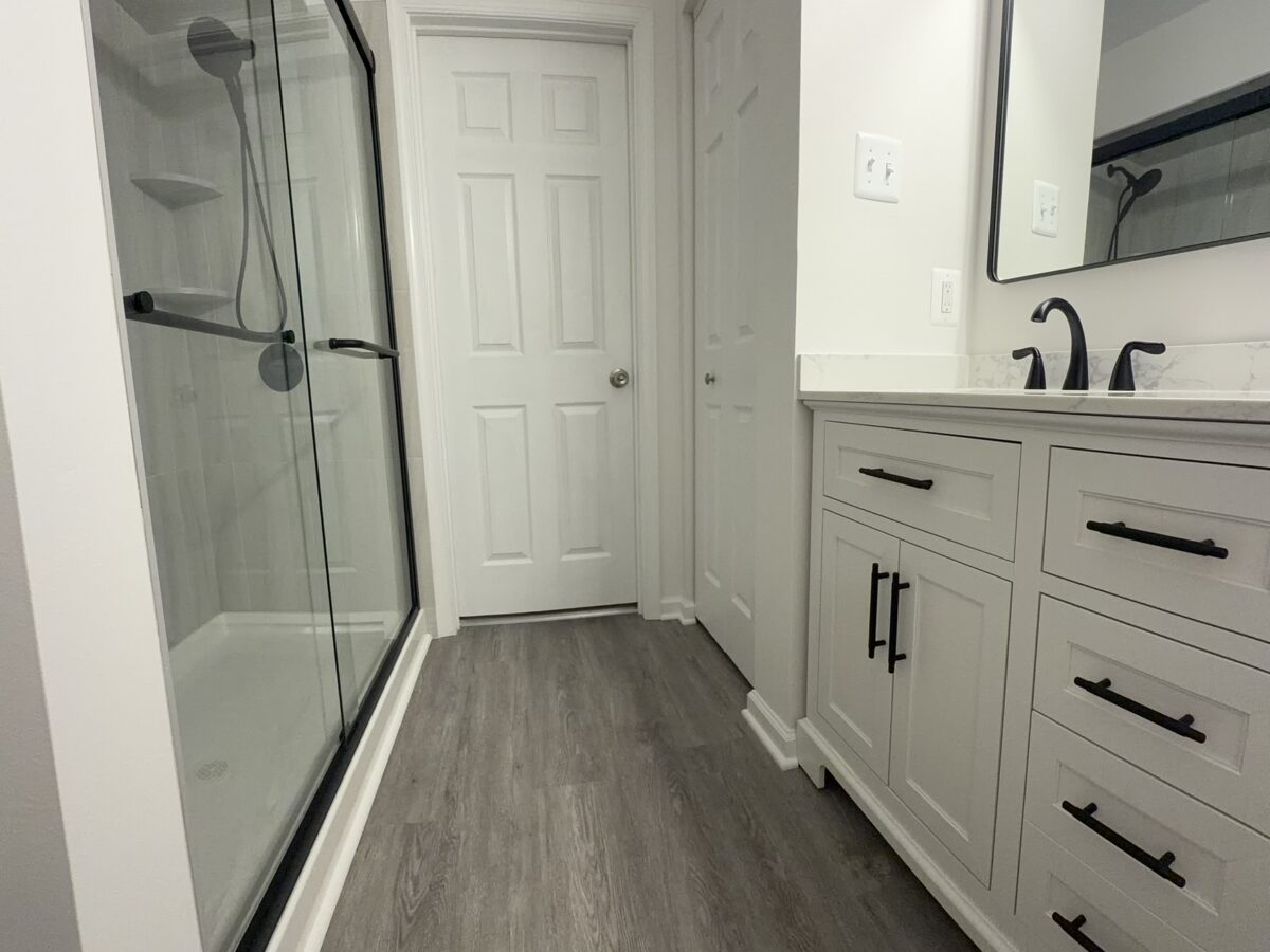 Bathroom Remodel with Double Vanity and Glass Shower White double vanity beside black-framed glass shower in remodeled bathroom