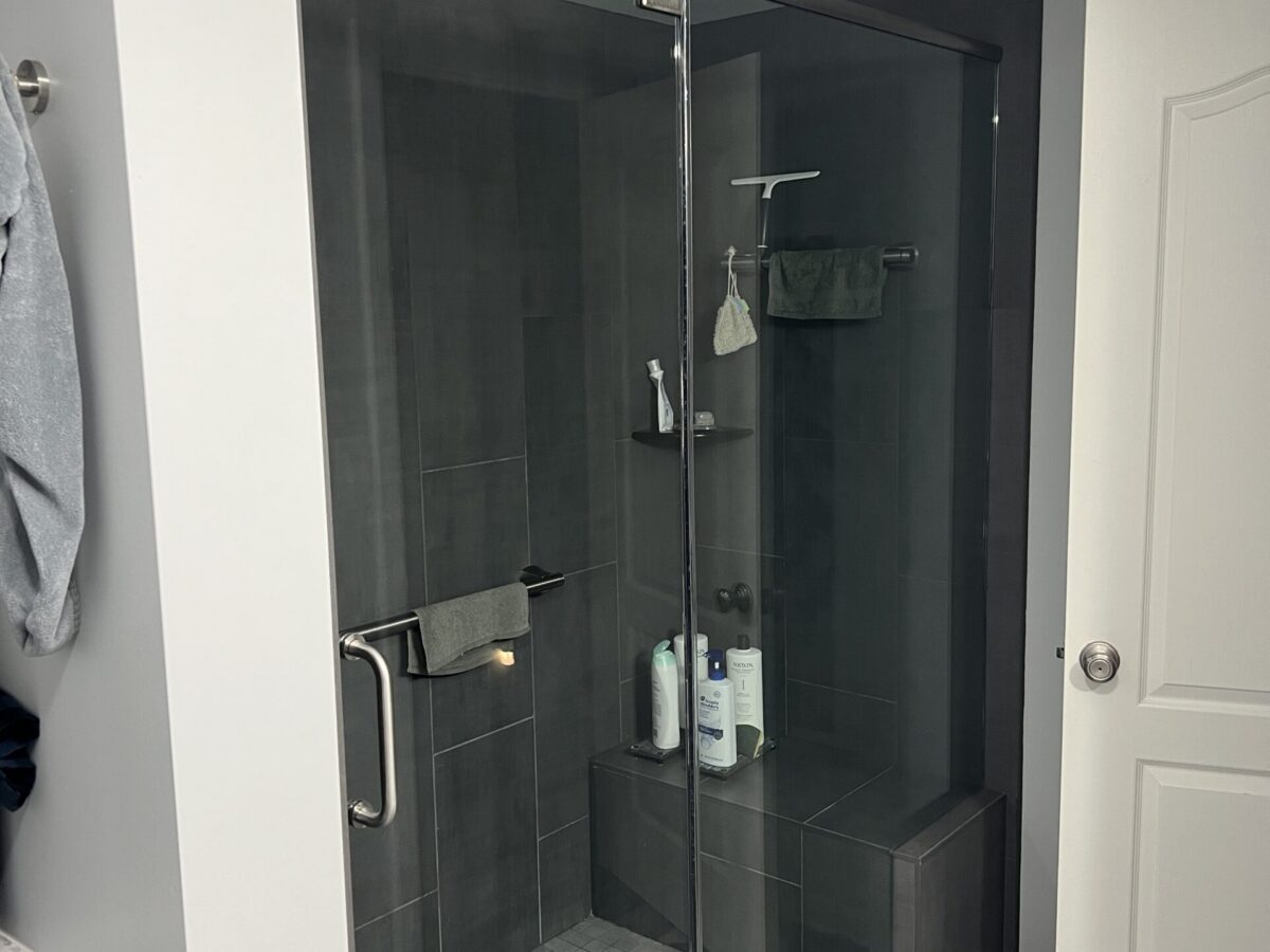 Dark Gray Tiled Shower with Built-In Bench Dark gray tiled shower with glass enclosure and built-in bench