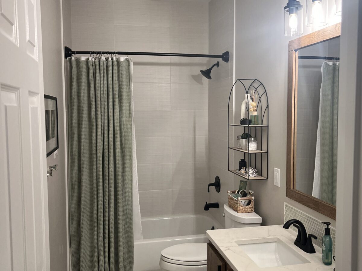 Bathroom Remodel with Wood Vanity and Tub-Shower Remodeled bathroom with wood vanity, tub and shower, and black fixtures