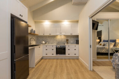 A kitchen with white cabinets and black appliances.