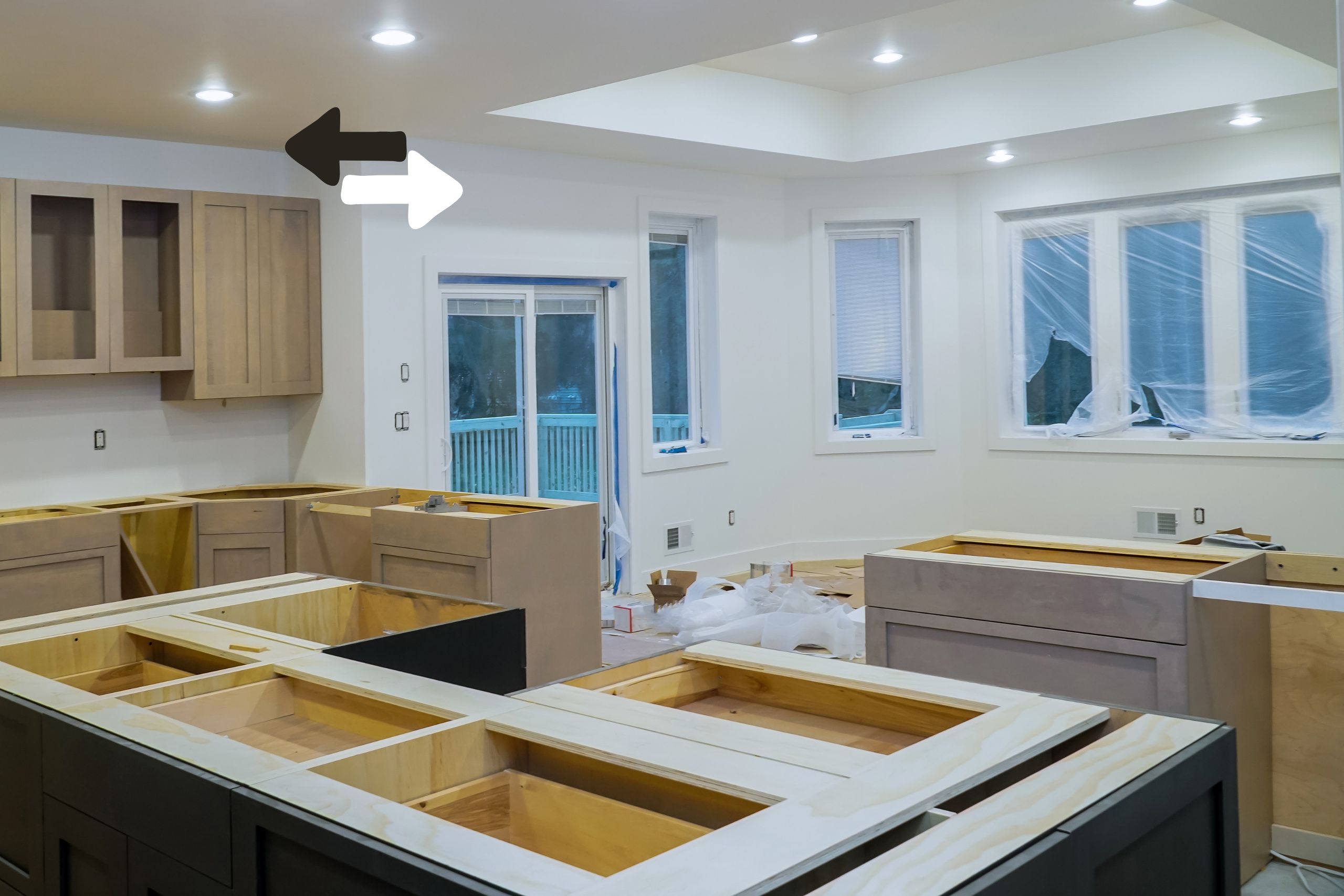 Modern kitchen addition under construction, featuring custom cabinetry and ample natural light from large windows and sliding doors.