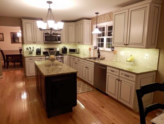 A kitchen with white cabinets and black island.