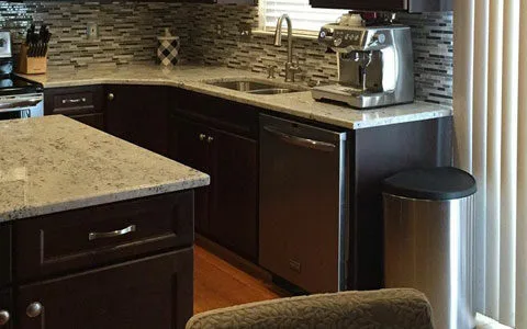 Modern design featuring island and surrounding cabinetry with granite countertops and tile backsplash.