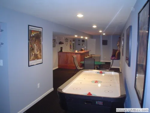 Basement recreation room featuring an air hockey table and a bar area in the background.