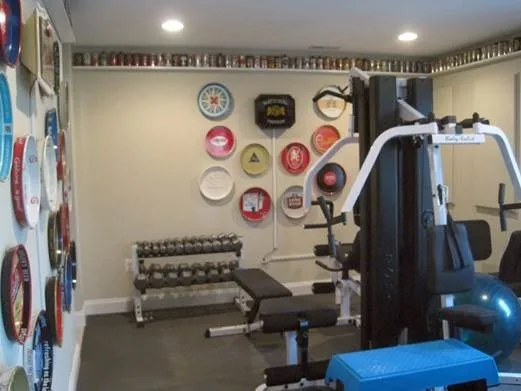 Home gym with weightlifting equipment and decorative wall plates in a remodeled basement.