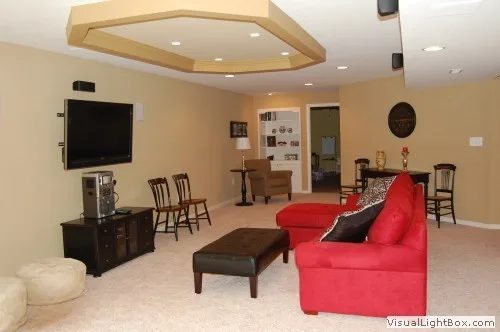 Basement living area with red sectional sofa, wall-mounted TV, and coffered ceiling design.