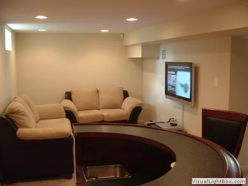 Cozy basement lounge area with a curved bar and wall-mounted television.