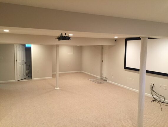 Spacious basement home theater with projector and blank wall screen setup.