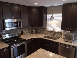 Modern renovated kitchen in Columbia, MD with dark cabinets, stainless steel appliances, granite countertops, and a stylish tile backsplash.