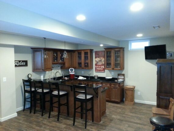 Spacious basement bar with wooden stools, cabinets, and ample seating space.