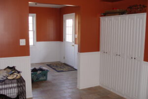 Interior view of mudroom with orange walls, white wainscoting, and built-in storage cabinets