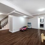 Finished basement playroom with hardwood floors, a staircase, and children's toys.