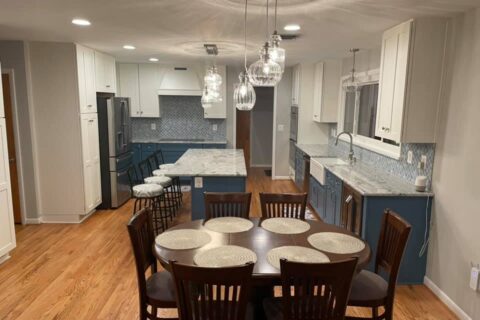 A dining room table and chairs in the center of a kitchen.