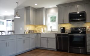 A kitchen with grey cabinets and black appliances.