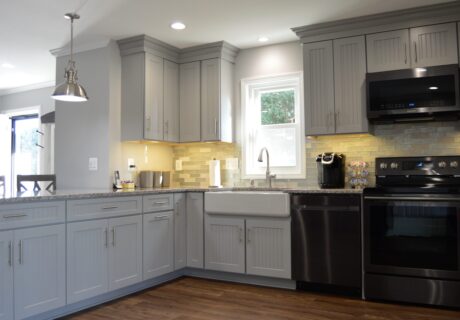 A kitchen with grey cabinets and black appliances.