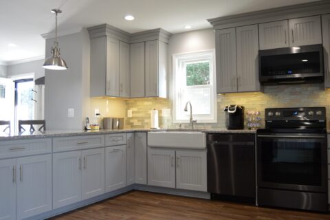 A kitchen with grey cabinets and black appliances.