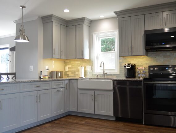 A kitchen with grey cabinets and black appliances.