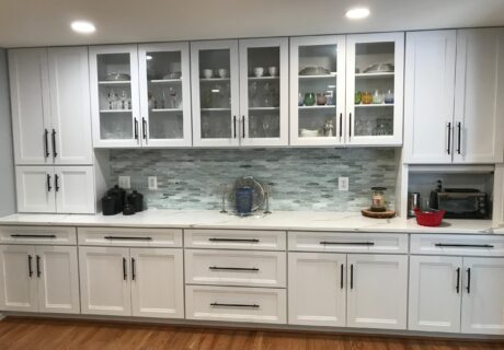 A kitchen with white cabinets and wooden floors