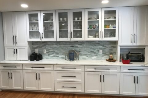 A kitchen with white cabinets and wooden floors