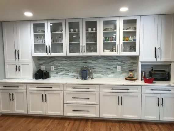 A kitchen with white cabinets and wooden floors