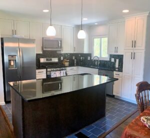 A kitchen with white cabinets and black counter tops.