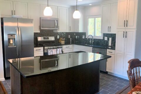 A kitchen with white cabinets and black counter tops.