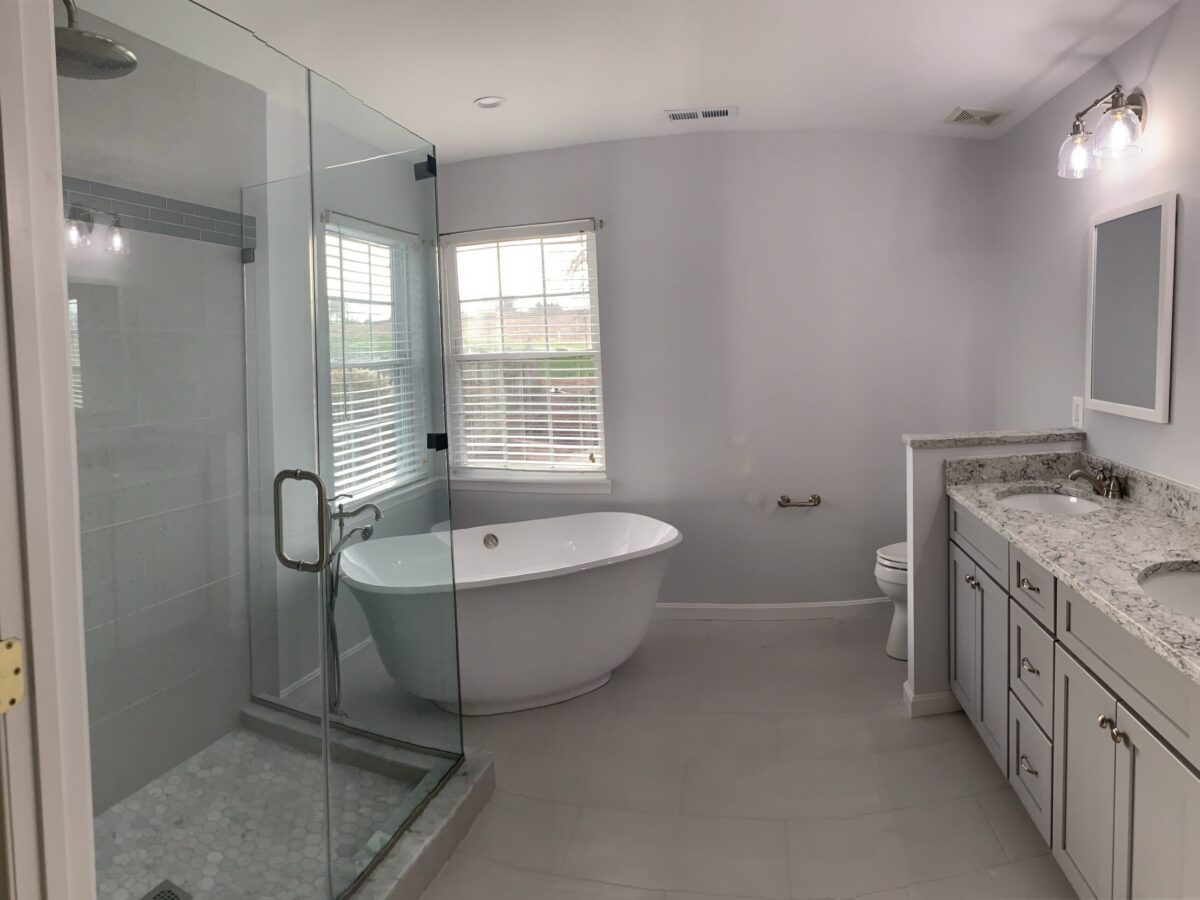 Deutsch (5) A bathroom with a large tub and glass shower door.