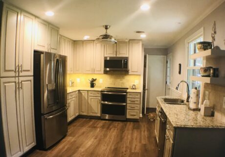 A kitchen with white cabinets and wood floors.