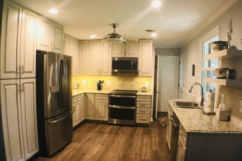 A kitchen with white cabinets and wood floors.