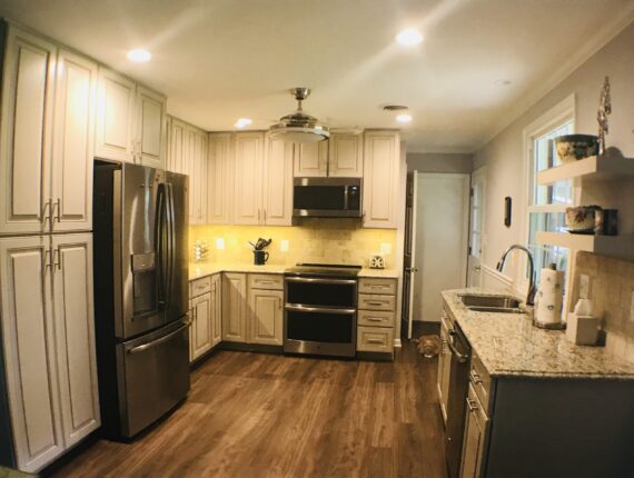 A kitchen with white cabinets and wood floors.