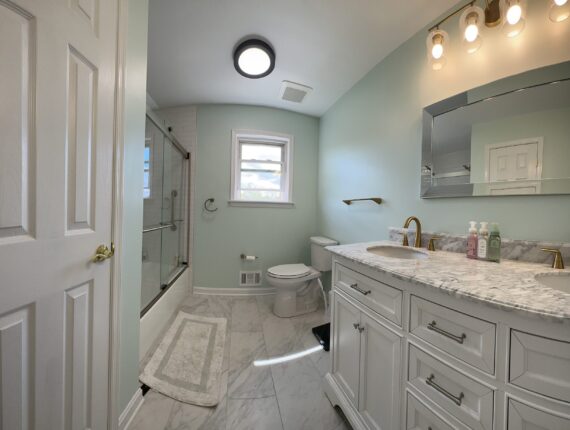 A bathroom with a toilet, sink and mirror.