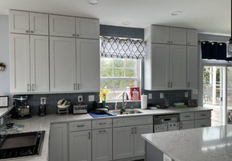 A kitchen with grey cabinets and white counters