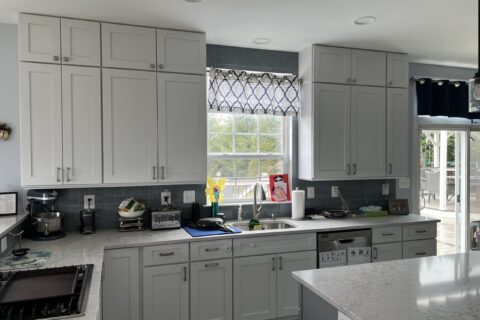 A kitchen with grey cabinets and white counters