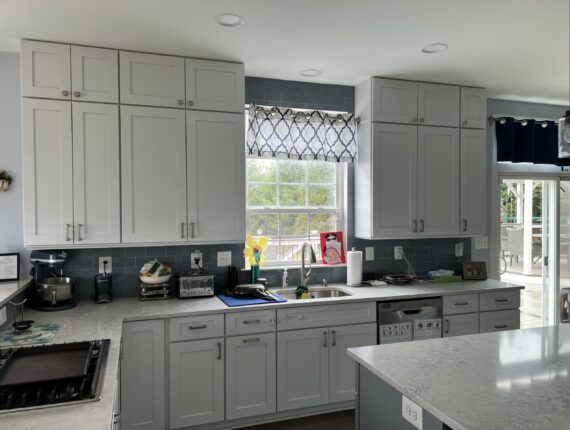 A kitchen with grey cabinets and white counters