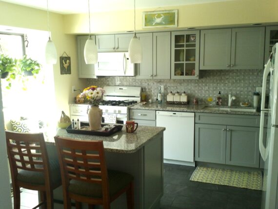 A kitchen with grey cabinets and white appliances.