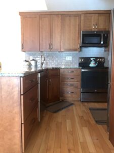 A kitchen with wood floors and black appliances.