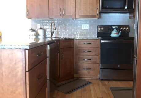 A kitchen with wood floors and black appliances.