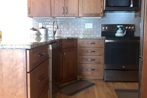 A kitchen with wood floors and black appliances.