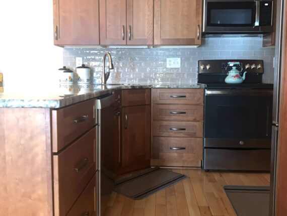 A kitchen with wood floors and black appliances.