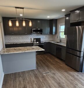 A kitchen with black cabinets and white walls.