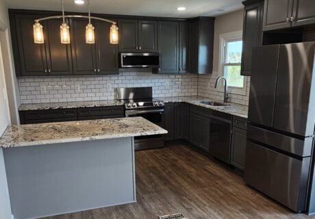 A kitchen with black cabinets and white walls.