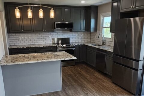 A kitchen with black cabinets and white walls.