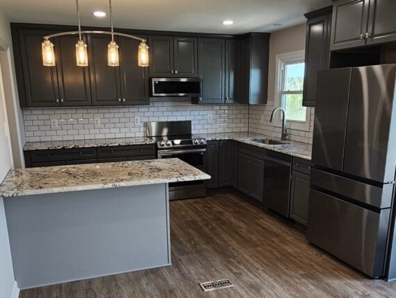 A kitchen with black cabinets and white walls.