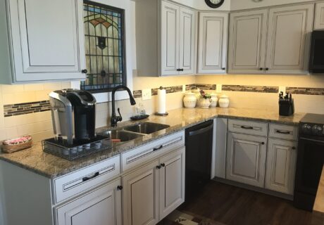 A kitchen with white cabinets and brown wood floors.
