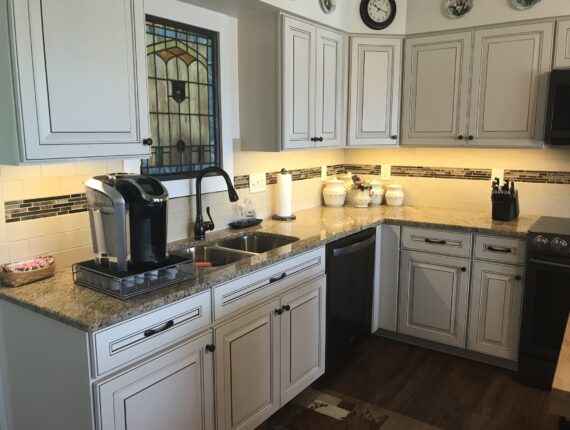 A kitchen with white cabinets and brown wood floors.