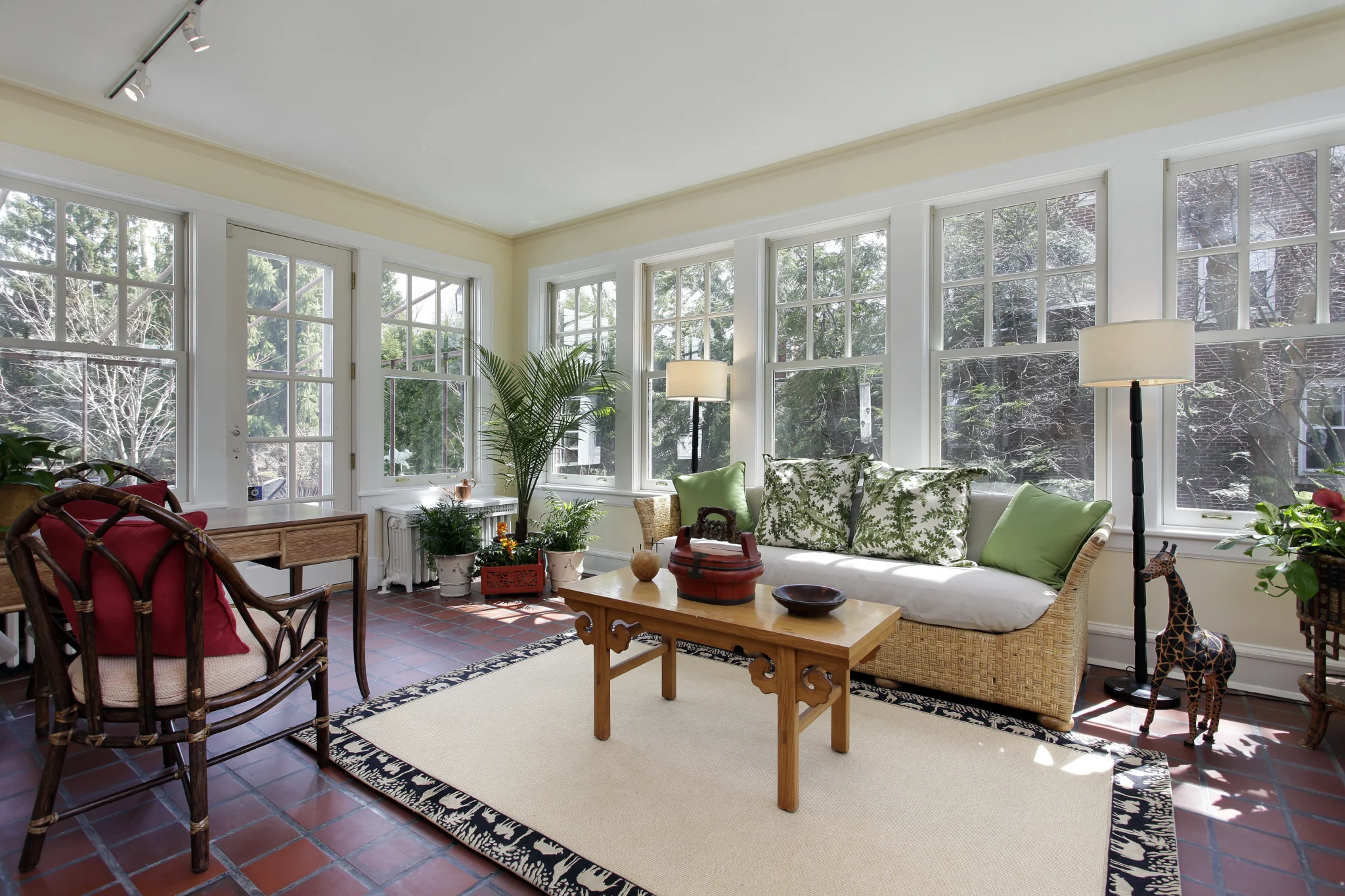 Bright sunroom addition with large windows, wicker seating, and natural light for a Frederick MD home addition